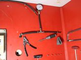 a red wall with a bunch of tools hanging on it