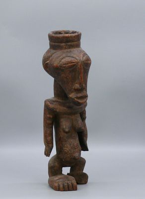 une petite statue en bois représentant un homme à la grosse tête