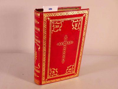 un livre rouge aux bords dorés, orné d'une croix