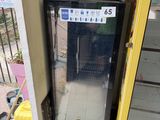 a refrigerator that is outside of a building with a fan in the background