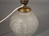 a white glass lamp with a gold base and a white cord