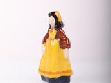 a small figurine of a woman in a yellow dress