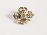 a close up of a flower shaped broochle on a white surface