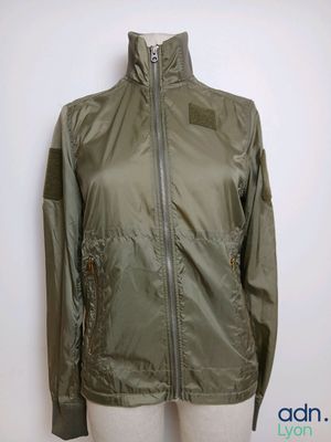 La veste est verte et comporte une fermeture éclair sur le devant.