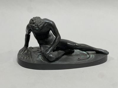 a statue of a man sitting on a surfboard on a white surface