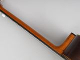 the back of an acoustic guitar with a wooden body and a black fret