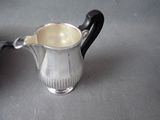 a silver pitcher on a table with a black handle