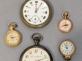 several different types of pocket watches are displayed on a gray surface