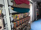 a woman that is standing in front of a rack of fabric