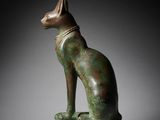 a bronze statue of a cat sitting on top of a marble block