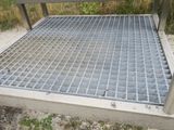 a metal grate on the ground next to a bench