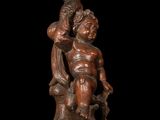 bronze statue of a boy holding a basket of fruit on top of a wooden base