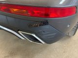 the rear end of a gray sports car parked in a garage