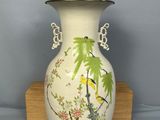 a white vase with a bird on it on a wooden stand