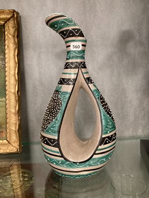 un vase posé sur une table à côté d'un tableau