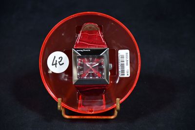 une montre rouge posée sur une assiette rouge, avec une étiquette de prix