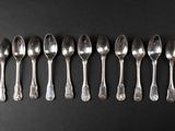 six silver spoons lined up in a row on a black surface