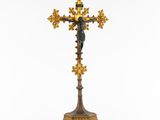 a gold and green cross with a statue on top of it