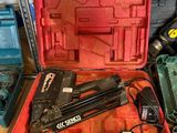 une boîte à outils rouge contenant un pistolet à clous et d'autres outils