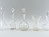 four clear glass vases are lined up on a white surface