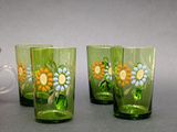 three glasses with flowers painted on them sitting on a table