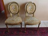 une paire de chaises anciennes aux assises rembourrées de motifs floraux, posées sur un tapis