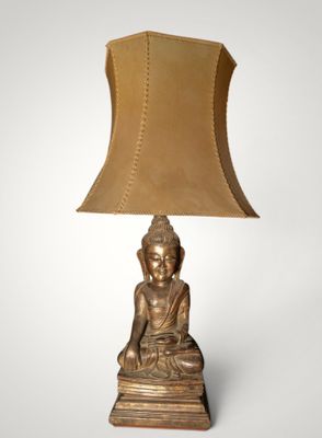 une lampe en forme de Bouddha doré, surmontée d'un abat-jour marron