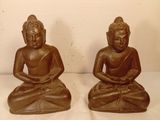 deux statues de bouddhas assis sur un socle blanc