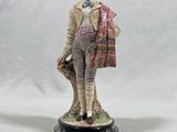 figurine of a boy with a hat and scarf holding a bag
