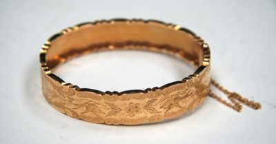 a close up of a gold bracelet on a white surface