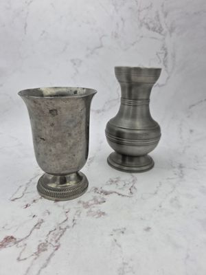 two silver vases sitting on a marble surface