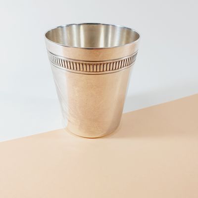 a silver cup sitting on top of a table next to a white wall
