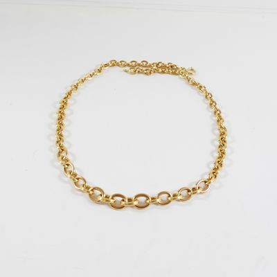 gros plan d'un bracelet en chaîne en or sur une surface blanche