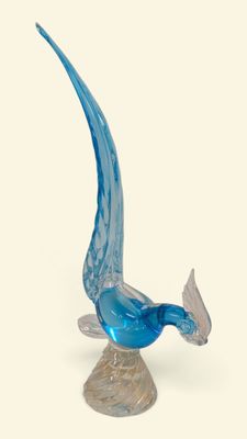 un oiseau en verre posé sur un socle