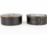 pair of black and white tinned containers on a white surface