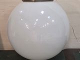 une grande lampe sphérique blanche posée sur une table près d'un mur
