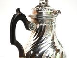 a silver coffee pot with a black handle on a white surface