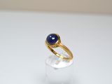 Gros plan sur une bague en or ornée d'une pierre bleue
