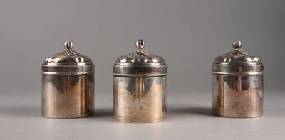 three silver canisters with lids on a table with a gray background