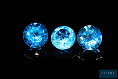 three blue topazte gems on a black background