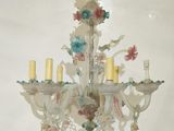 a chandelier with flowers and candles hanging from it