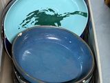 une boîte remplie d'assiettes bleues et vertes posée par terre