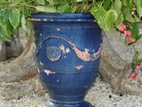 a blue vase with a plant in it sitting on the ground