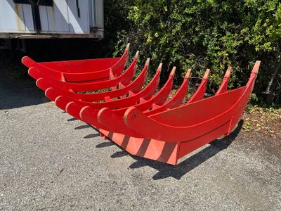six canoës rouges alignés au bord de la route