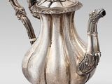 une théière ancienne en argent, dotée d'une anse en forme d'oiseau et posée sur un socle