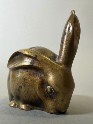 un petit lapin en bronze posé sur une table