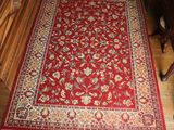 a close up of a red rug on a wooden floor