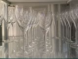 many empty wine glasses lined up on a glass shelf