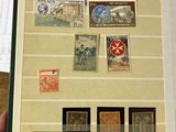 Quelqu'un tient sur une table un livre sur lequel sont apposés des timbres.