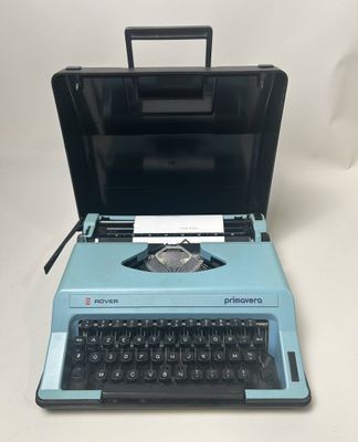 une vieille machine à écrire bleue posée sur une table blanche